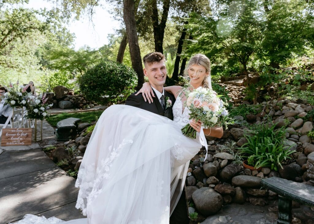 Groom picks up bride and carries her after their wedding ceremony in Northern California