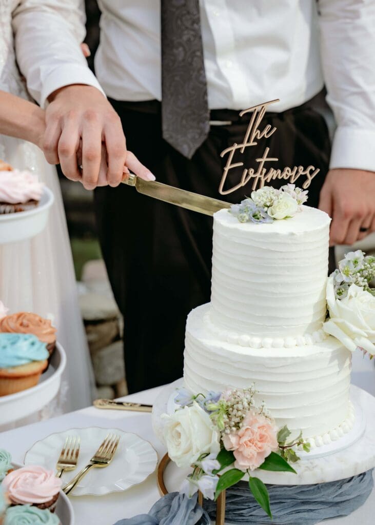 Close up up bride and groom's hands as they cut their wedding cake