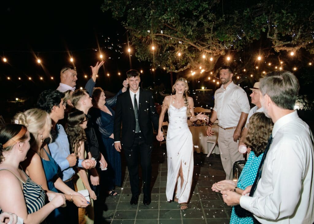 Flash image of the Bride and groom exiting their reception walking through 2 lines of guests walking toward the camera smiling