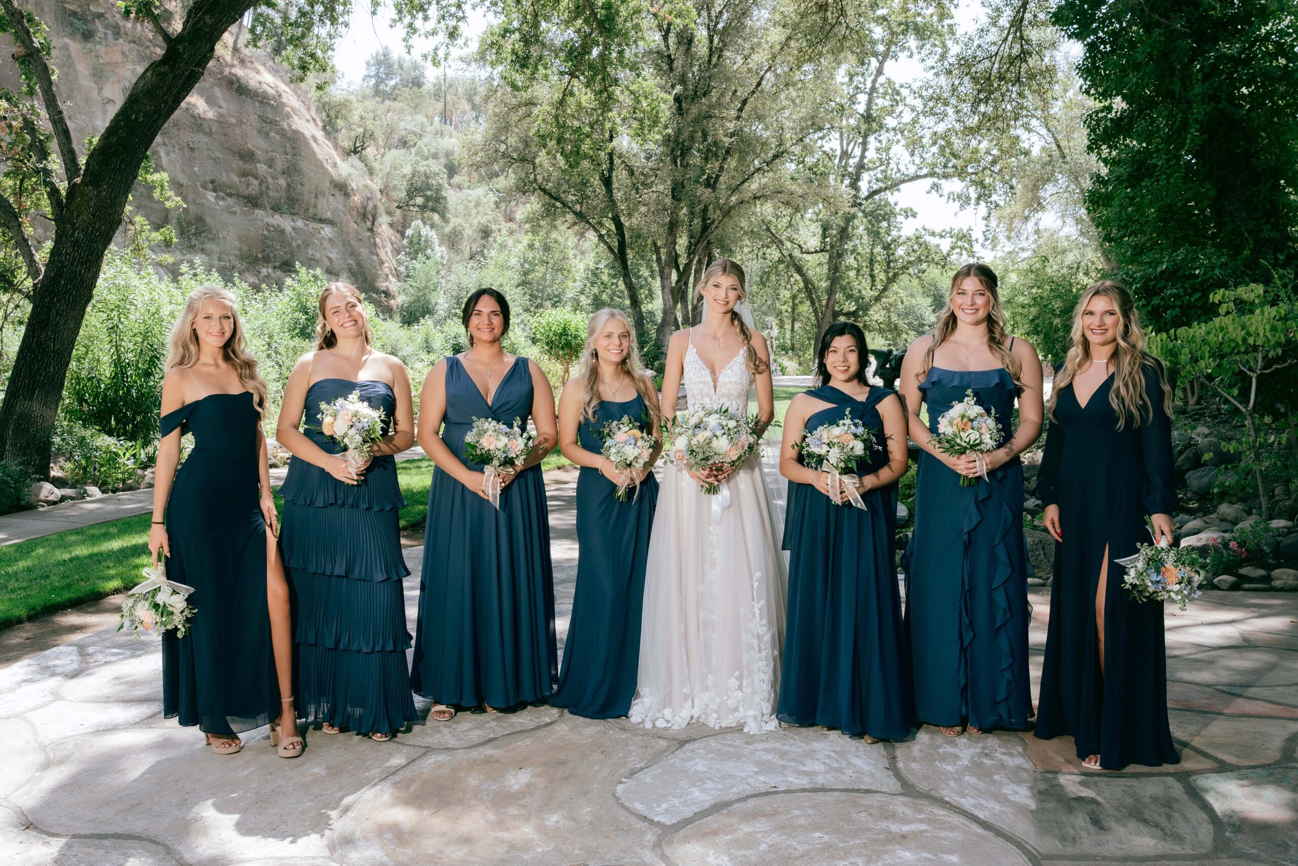 Lineup of 7 bridesmaids with bride in the middle all holding bouquets