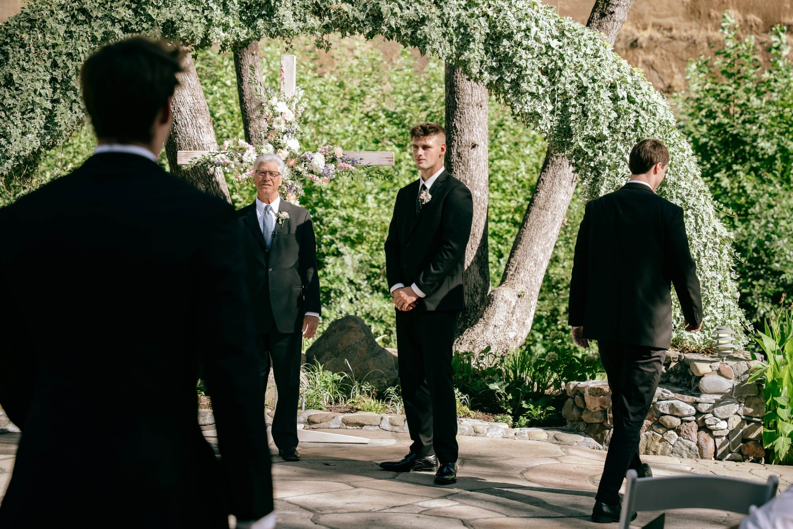 Groom standing at the alter while his groomsmen walk down the aisle during outdoor wedding ceremony at Centerville Estates