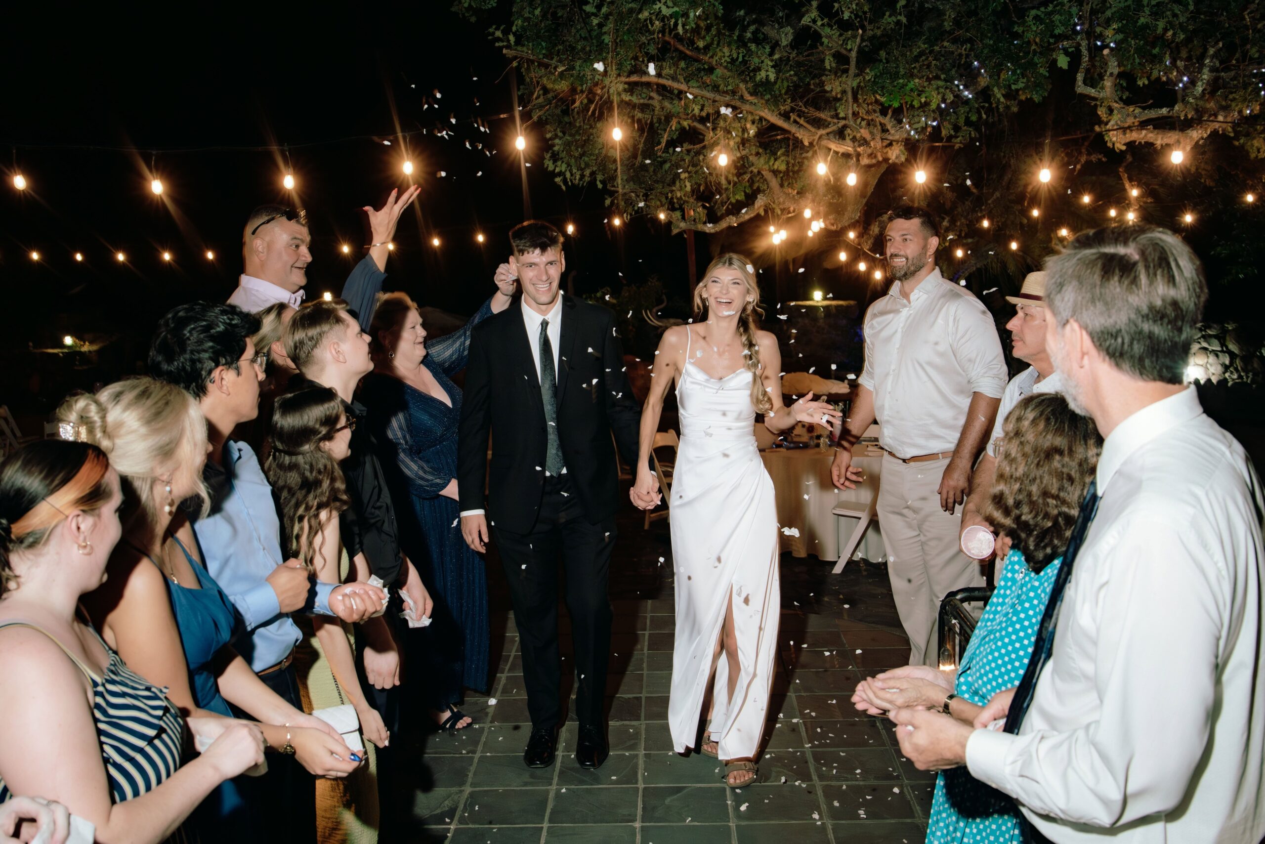 Flash image of the Bride and groom exiting their reception walking through 2 lines of guests walking toward the camera smiling