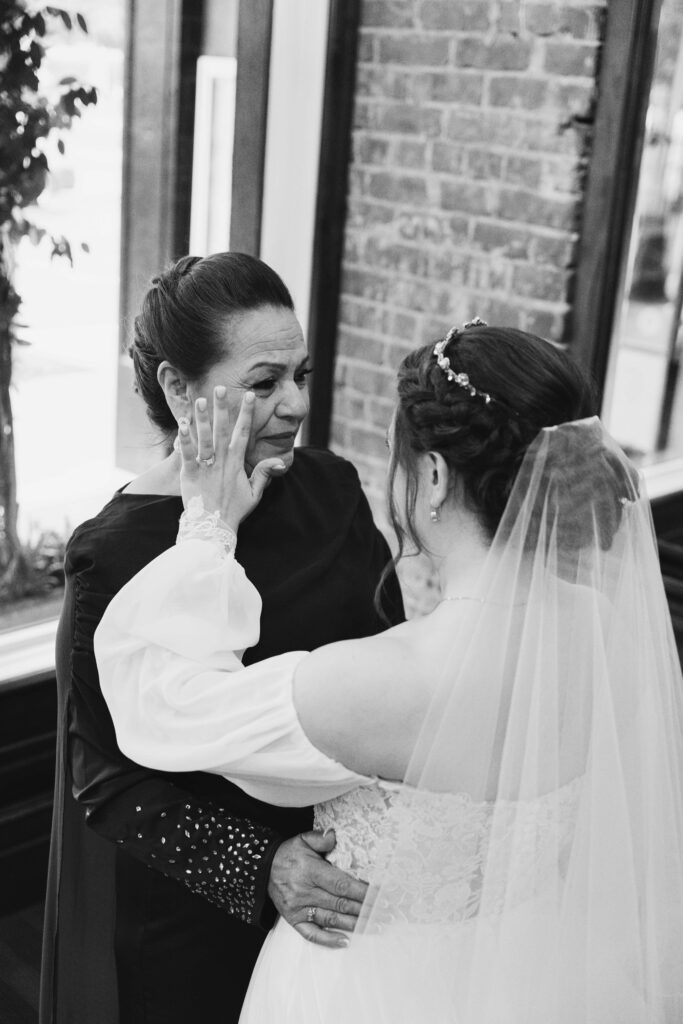 Black and white image of Mother-in-law first look with bride as the bride wipes her new mother's tears away